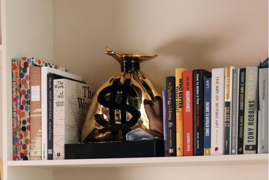 The gold money-bag sculpture among the business books of the library